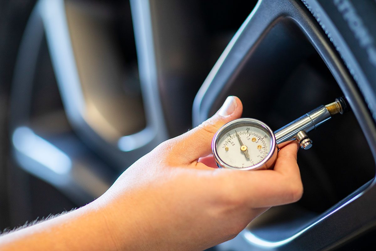 Hand holding pressure gauge for car tire