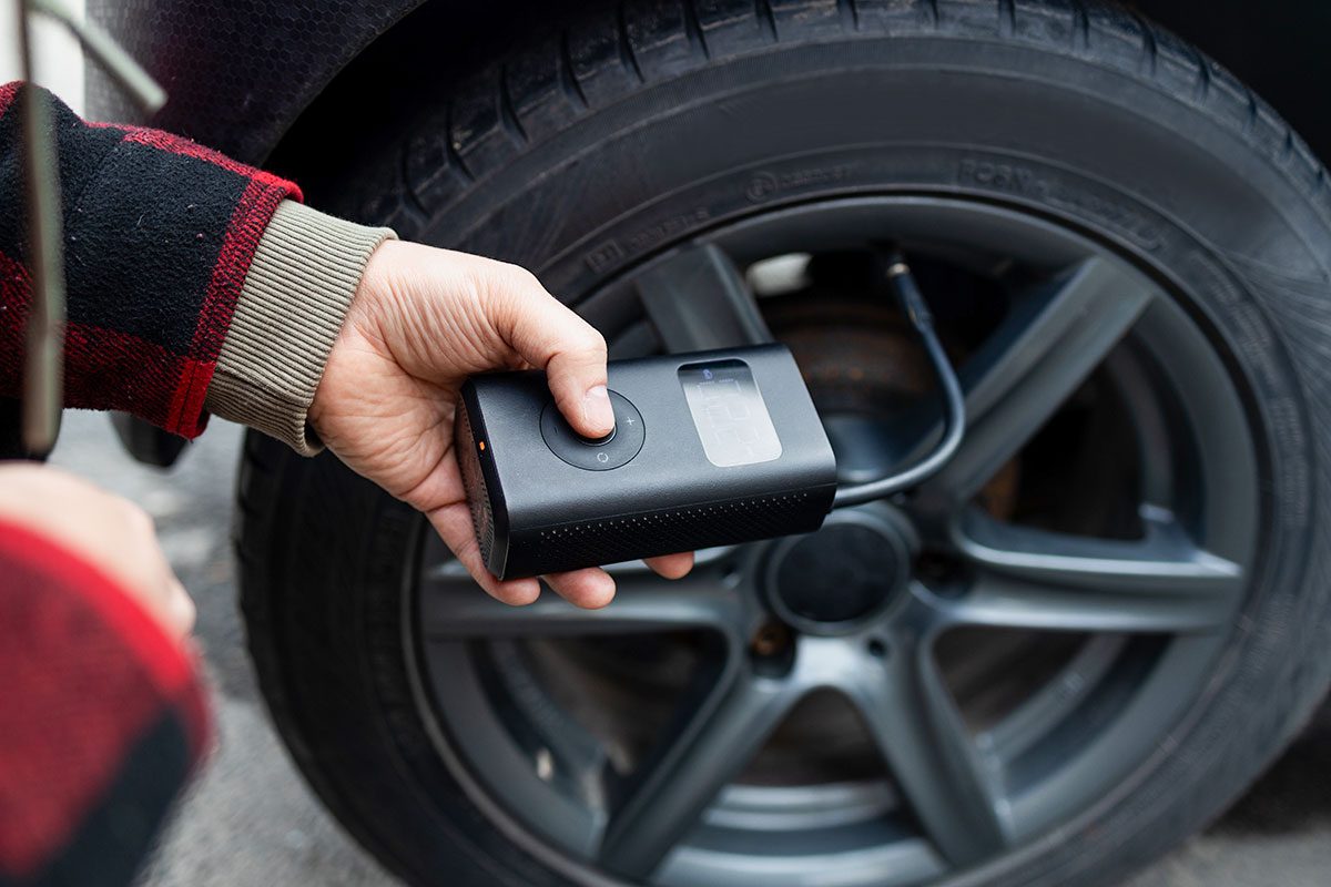 Close up of man hand holds a wireless portable air pump for inflating car tires