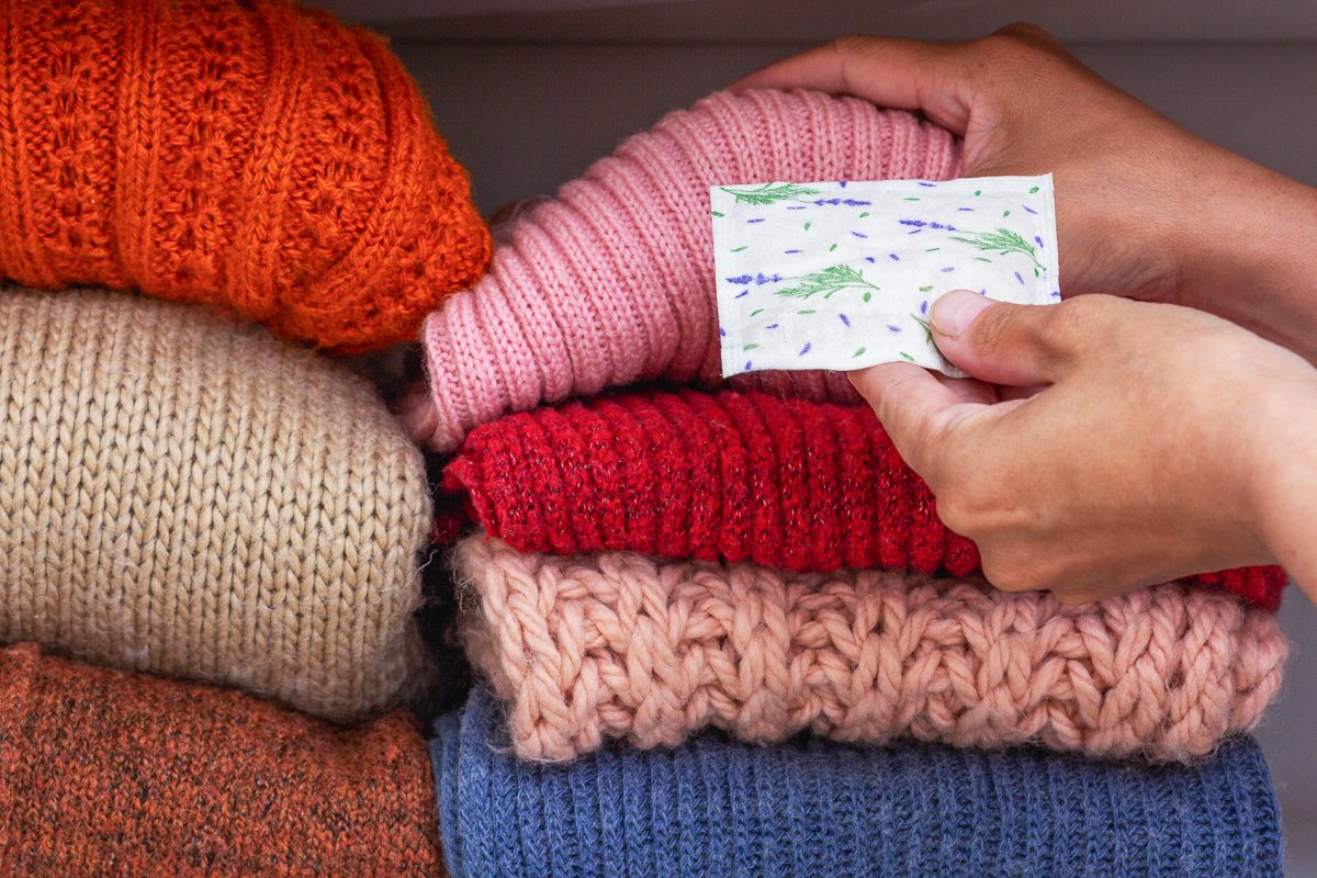 hands putting lavender sachet between clothes