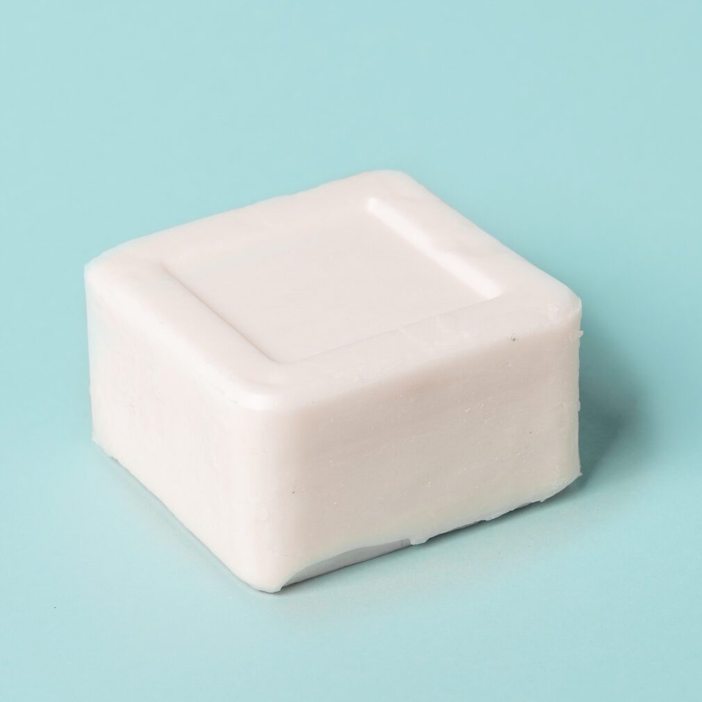 White bar of soap lying on a blue background, minimalistic concept