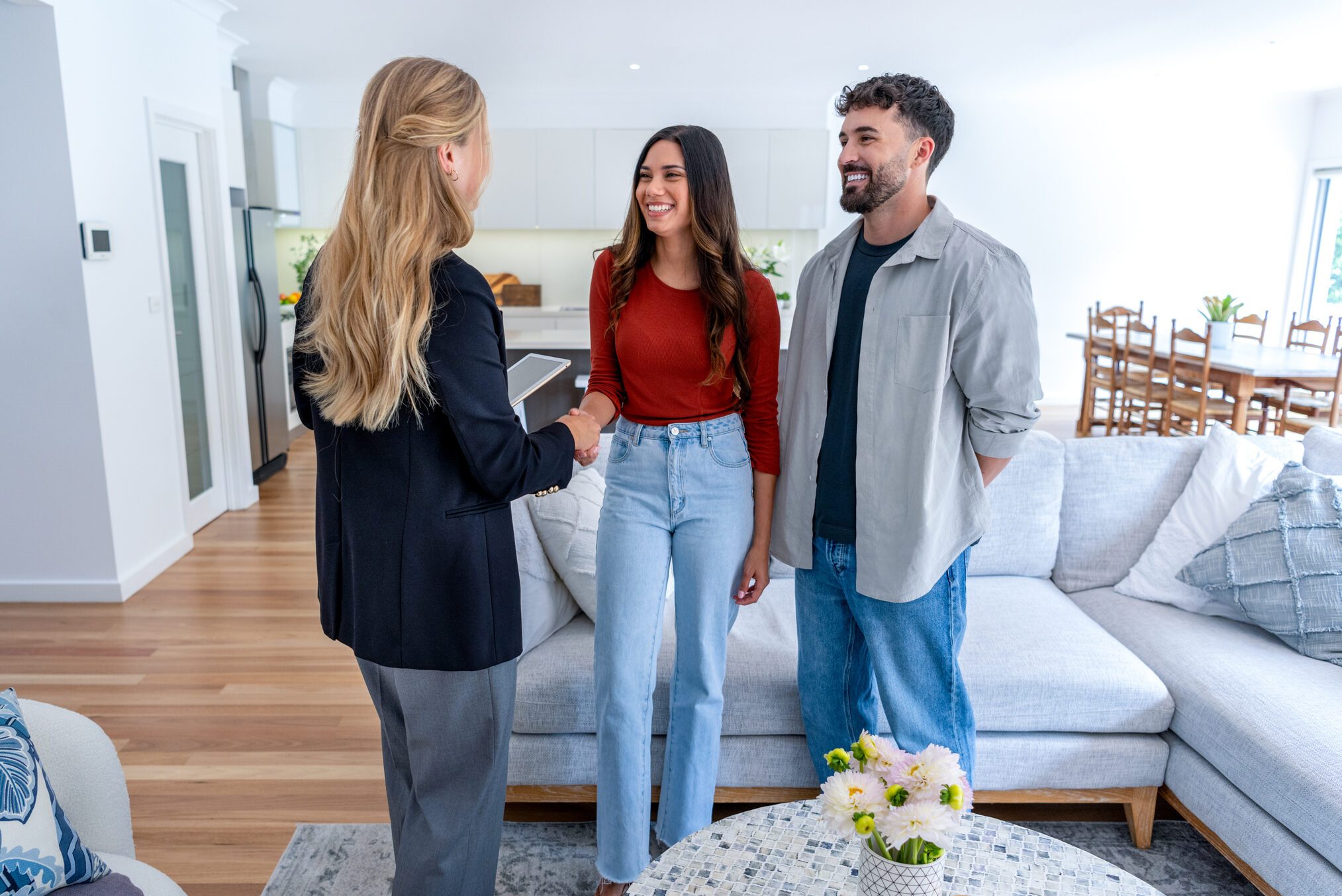 Real estate agent with couple in luxury home. They are shaking hands
