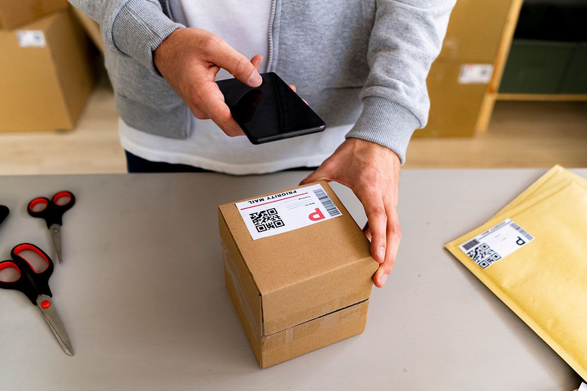 Businessman scanning QR code on box through smart phone at desk