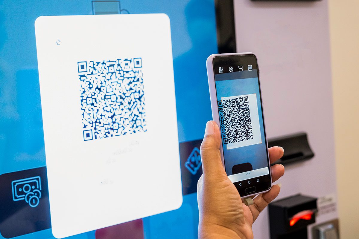 Hands using mobile phone paying the soft drink at vending machine