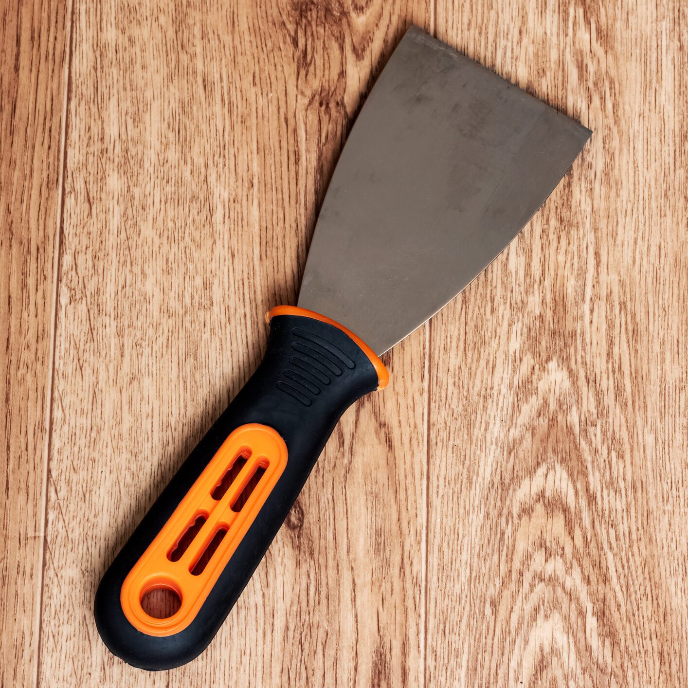 Paint spatula with black handle on wooden background