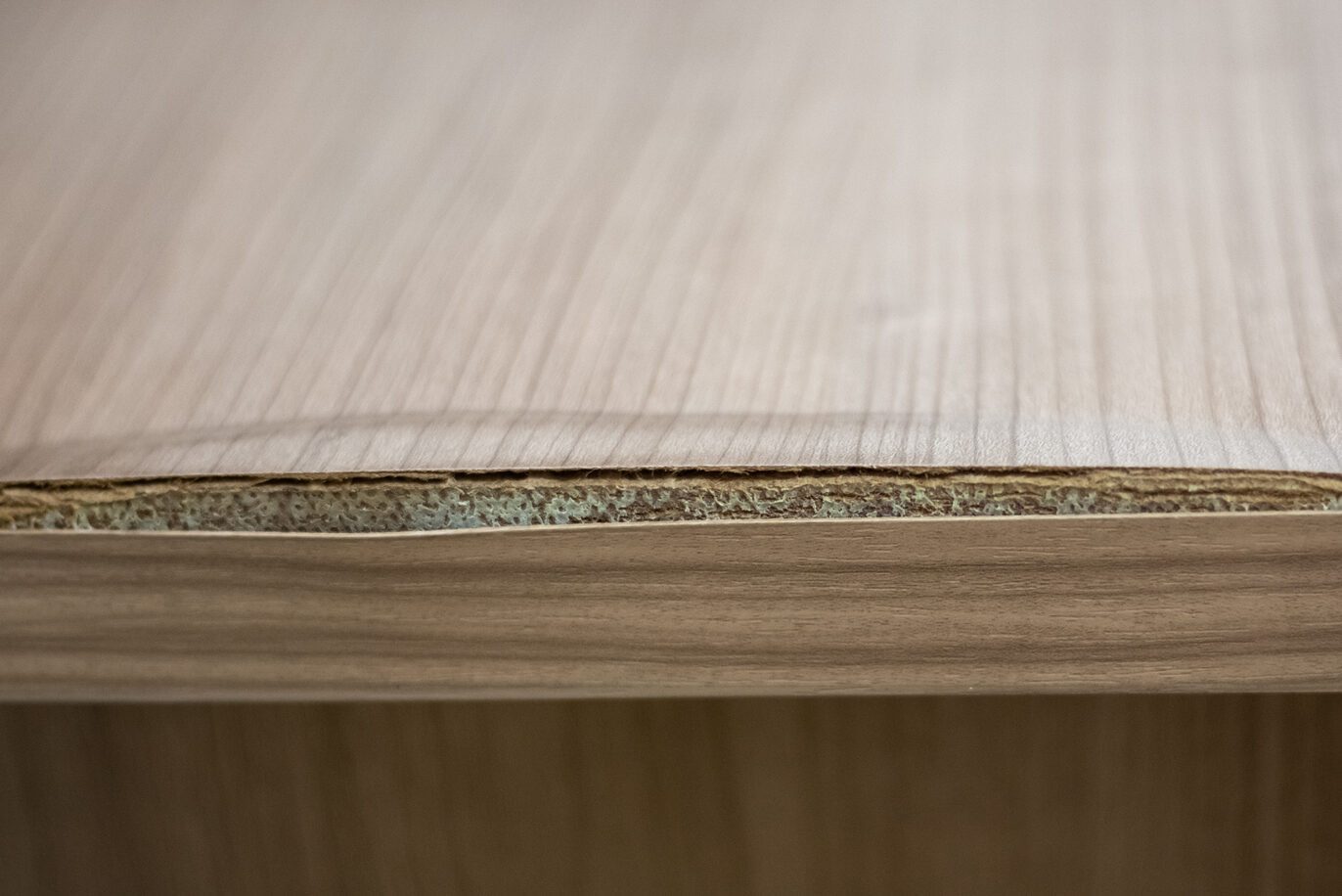 Chipboard table with delaminated edge due to humidity. Wooden surface care
