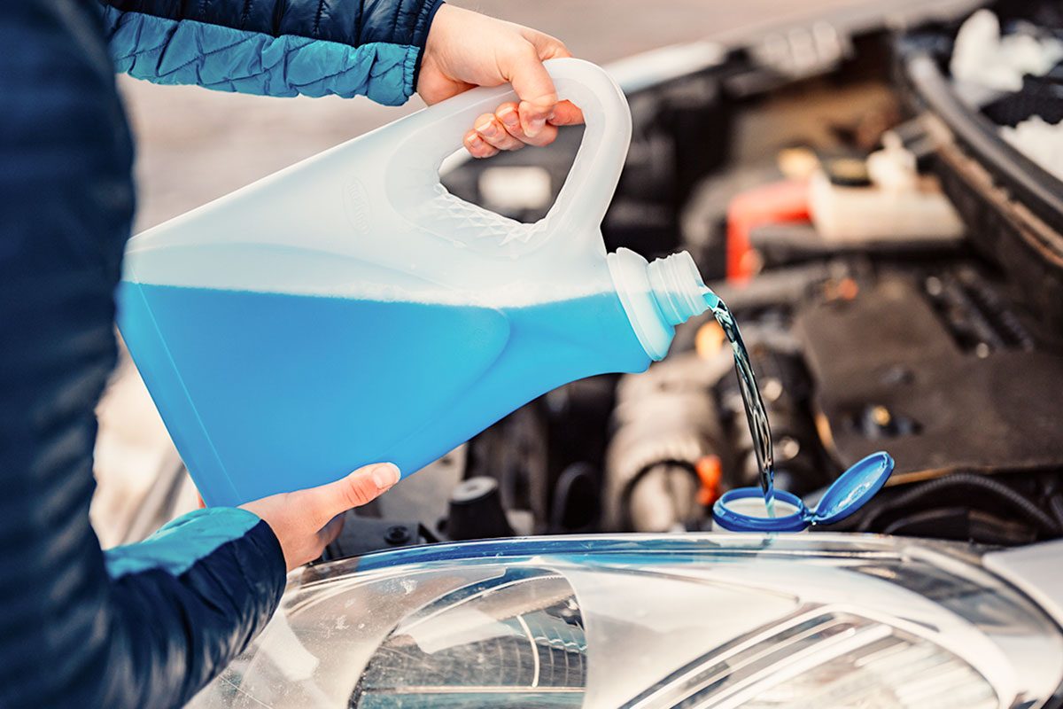Pouring antifreeze. Filling a windshield washer tank with an antifreeze in winter cold weather.