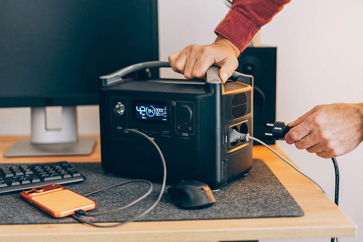 Freelancer, man using charging station at home white blackout. 