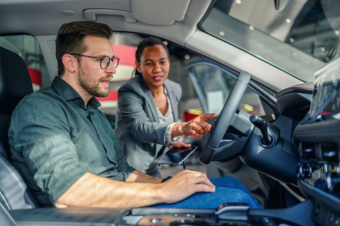 Saleswoman helping the male customer to choose a new car