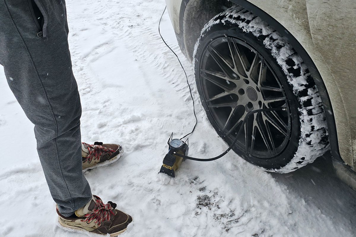 Pumping Car Tire in Snowy Winter Conditions