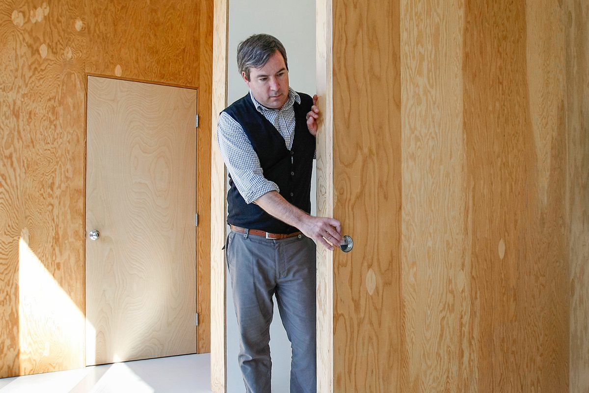 oe Sola closes large plywood wooden doors in the second floor of his house